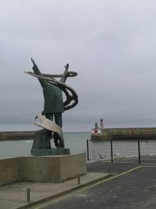 a statue of a person with a skateboard in front of the ocean at La maison du bonheur in Port-en-Bessin-Huppain