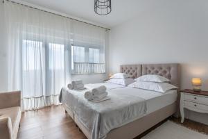 a white bedroom with a large bed with towels on it at Melki for 12 people with private pool in Klis