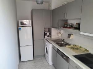 a kitchen with a white refrigerator and a dishwasher at Royal Palm Juan les pins -Appartement 53M2 avec terrasse ensolleillée 5e dernier étage 200m de la plage in Juan-les-Pins