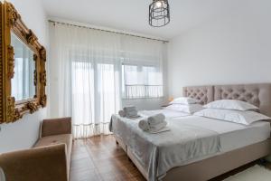 a white bedroom with a large bed and a mirror at Melki for 12 people with private pool in Klis