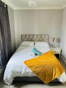 a bedroom with a white bed with a yellow blanket at Esplanade lodge in Strood