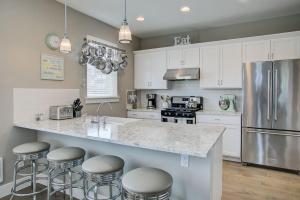 una cocina con armarios blancos y una isla con taburetes. en Sand Castle Cottage - Oyhut Bay Seaside Village en Ocean Shores