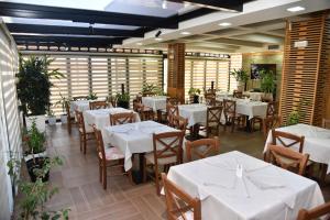 a restaurant with white tables and chairs and plants at Hotel Imperiale in Durrës