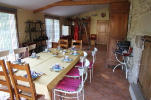 a dining room with a long table and chairs at Au Figuier du Gué in Lantillac