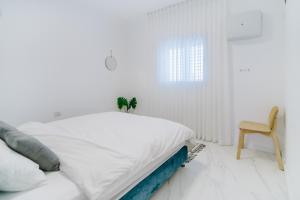 um quarto branco com uma cama e uma cadeira em Yaffo Joy - Penthouse Apartment em Tel Aviv