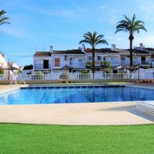 a large swimming pool with palm trees and houses at Bungalow los Majuelos in Gran Alacant