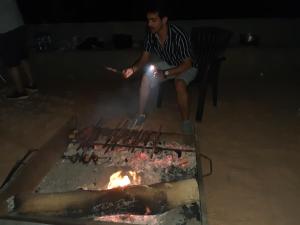 a man sitting on a chair next to a fire at happiness camp in Wadi Rum