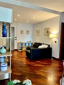 a living room with a black couch and a wooden floor at INTERO APPARTAMENTO EUR Torrino NUOVO LiFeHome in Rome