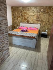 a bed with pink pillows in a room with a stone wall at Vila Vlad in 2 Mai