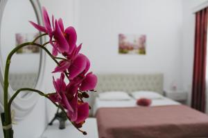 un montón de flores púrpuras en una habitación con cama en HC Hotel & Suites, en Vlorë