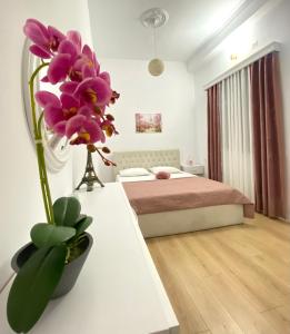 1 dormitorio con 1 cama y un jarrón con flores púrpuras en HC Hotel & Suites, en Vlorë
