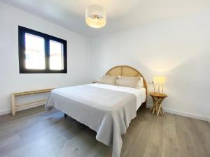een slaapkamer met een bed met een witte sprei en een raam bij Apartamento recién reformado para 6 personas in Port de Pollença