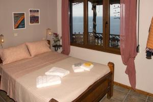 a bedroom with a bed with towels and a window at Balcony on the Rocks in Agii Saranta
