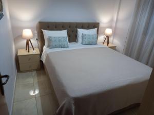 a bedroom with a large white bed with two lamps at Elena House in Kalamaki Heraklion