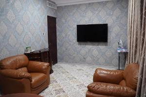 a living room with two leather chairs and a television at Gulistan Hotel in Dushanbe