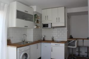 kuchnia z białymi szafkami i pralką w obiekcie Beautiful brand new 2 bedroom flat with terrace w Maladze