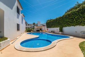 a swimming pool in a yard next to a white building at Appartement ALGARDEN Olhos d'Agua in Olhos de Água