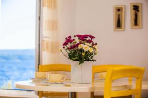 a table with yellow chairs and a vase of flowers at Beach Holiday Home Laura in Mimice +20 photos