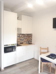 a white kitchen with white cabinets and a table at Apartman ''Nicole'' in Pula