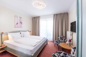 um quarto de hotel com uma cama e uma mesa e uma televisão em Die WUNDER s Ferienpension em Pörtschach am Wörthersee