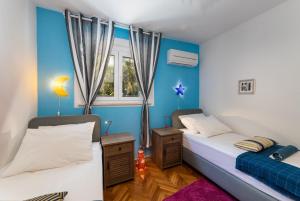 two beds in a room with blue walls at Family in Gradac