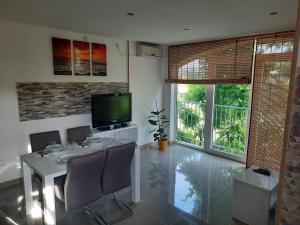 a dining room with a white table and a television at Apartmani Scripea in Škrip