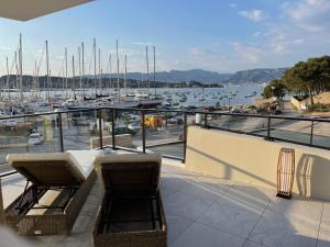 balkon z 2 krzesłami oraz przystań z łodziami w obiekcie Superbe appartement bord de mer w mieście Saint-Mandrier-sur-Mer