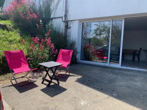 dos sillas rosas y una mesa frente a una casa en suite junior OMAHA BEACH, en Flers