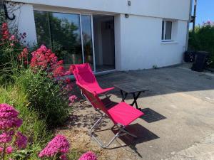 dos sillas rosas y una mesa frente a una casa en suite junior OMAHA BEACH, en Flers