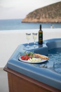 una mesa con un plato de comida y dos copas de vino en white house apollon naxos en Apollon