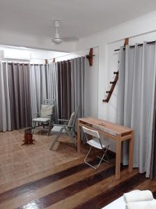 a room with a table and chairs and curtains at Residencial Brigada in Santo António