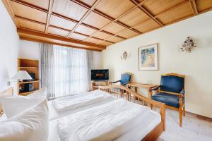 1 dormitorio con 1 cama, escritorio y sillas en Hotel Nuss, en Grainau