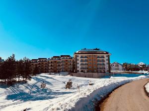 een gebouw op een besneeuwde heuvel met een weg bij Lux Apartmani Vojinović in Zlatibor