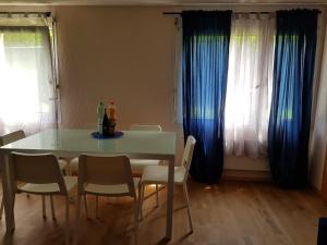 a dining room table and chairs with blue curtains at 2 Rooms cosy Apartment near Liechtenstein in Haag
