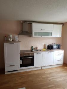 a kitchen with white cabinets and a stove top oven at 2 Rooms cosy Apartment near Liechtenstein in Haag
