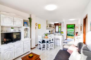 salon z kanapą i telewizorem oraz kuchnia w obiekcie Apartamento con vistas al mar-Ola del atardecer w mieście Mogro