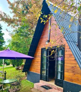 a small house with a purple umbrella and a table at Villa Vintage Campos - Piscina e opções de suites com hidromassagem in Campos do Jordão