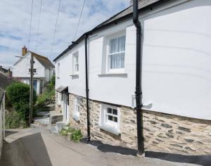 een wit huis met witte ramen aan een straat bij Bre Cottage in Port Isaac