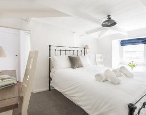 een slaapkamer met een groot wit bed en een bureau bij Bre Cottage in Port Isaac