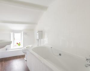 een witte badkamer met een bad en een toilet bij Bre Cottage in Port Isaac +11 foto's