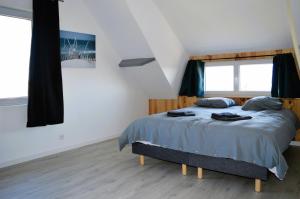 ein Schlafzimmer mit einem Bett mit blauer Bettdecke in der Unterkunft La maison penchée, avec jardin à 50m de la plage in Asnelles