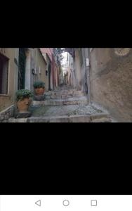 an image of an alley way with potted plants at Al Teatro Antico Rooms & House in Taormina