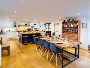 a kitchen with a long wooden table and blue chairs at Flaska House in Penrith