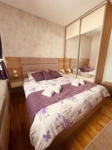 Un dormitorio con una cama grande con un espejo grande. en Apartmani Vojinović, en Zlatibor