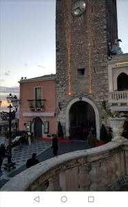 un edificio con una torre con un reloj. en Al Teatro Antico Rooms & House en Taormina