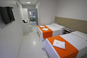 a hotel room with two beds and a flat screen tv at Hotel Encantos de Penedo Alagoas in Penedo