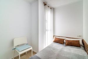 1 dormitorio blanco con 1 cama y 1 silla en Precioso apartamento con Jacuzzi, en Torremolinos