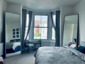 a bedroom with two mirrors and a bed and a window at Southsea Retreat in Southsea