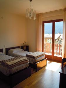 a bedroom with two beds and a large window at Appartamenti Rosenberger in Molveno