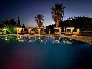 a swimming pool at night with palm trees and lights at Avra Sunset Sea View Liapades in Liapades